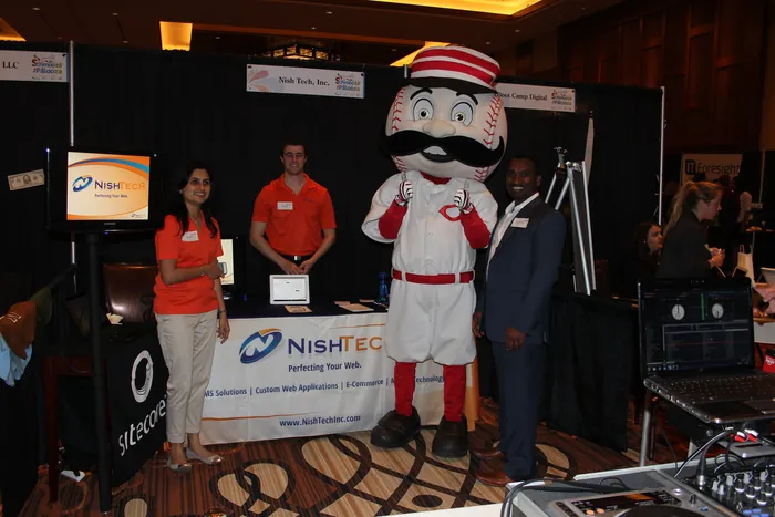 The first Nishtech expo booth, the team in orange shirts alongside the Cincinnati Reds mascot.