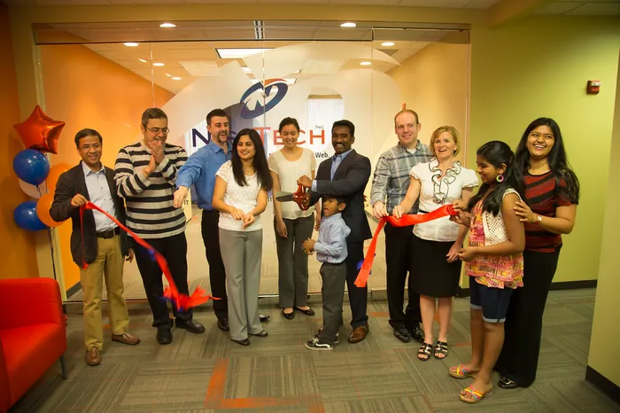 The Nishtech team cutting the ribbon on a larger office, 2015.