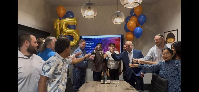 The Nishtech team raising a toast to fifteen years, with the new nishtech.com on the screen behind them.
